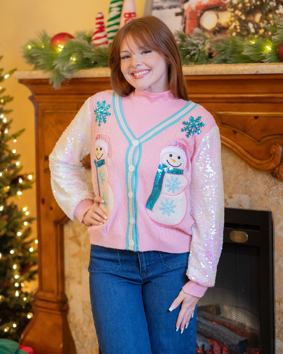 Person wearing a pink sweater with snowman designs in a festive setting.